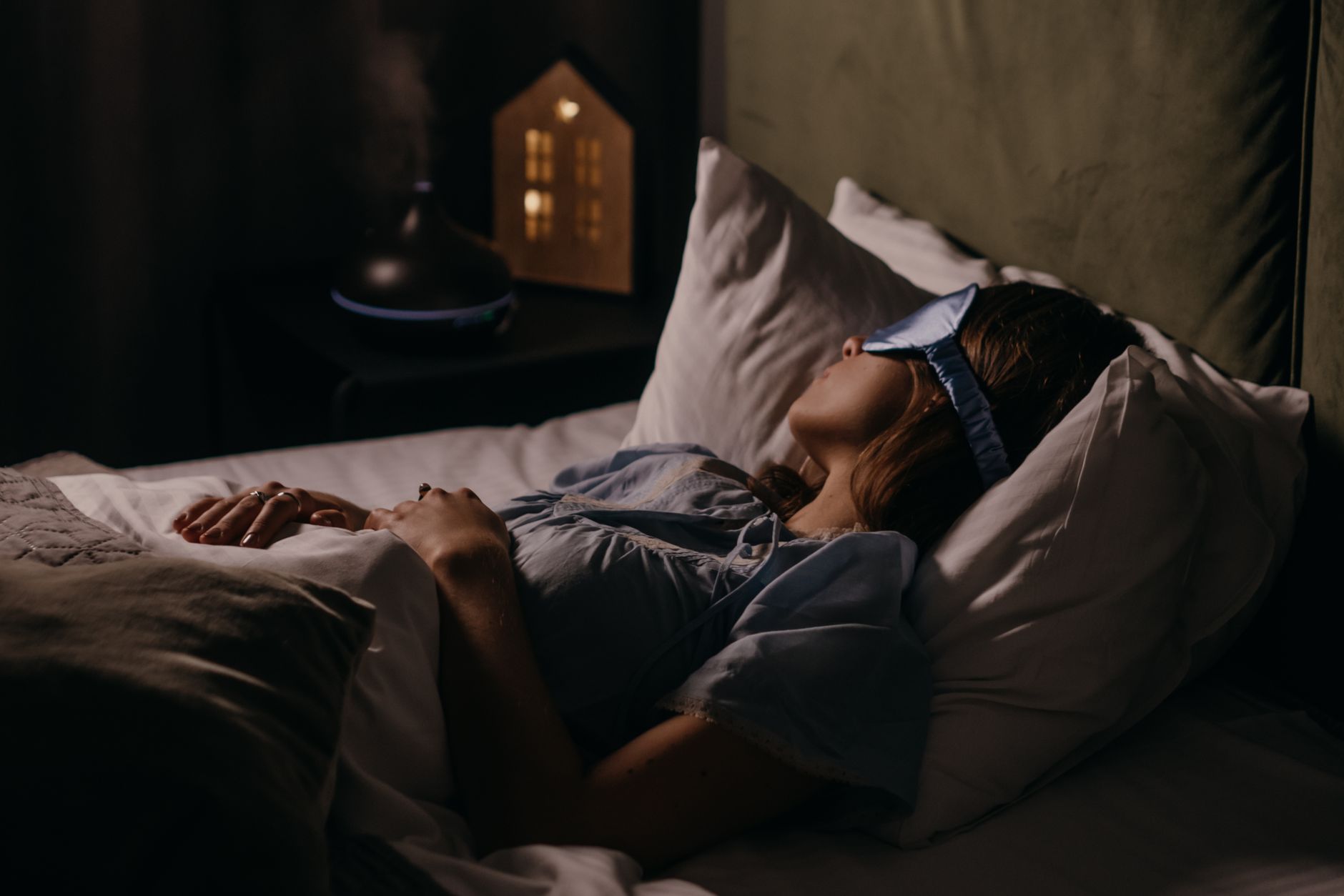 アイマスクをして静かに眠る女性、薄明かりの寝室