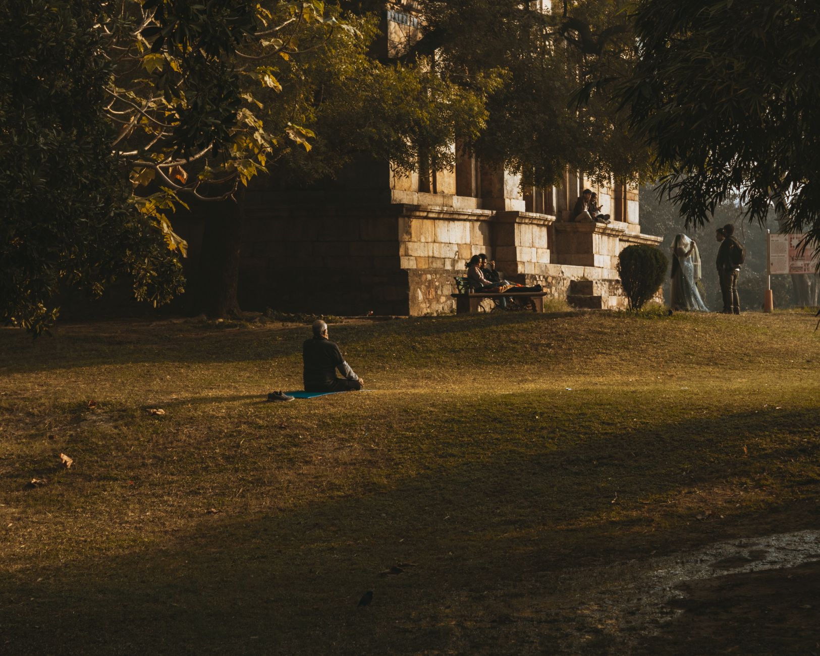 公園の芝生にマットを敷いて静かに座る人の遠景