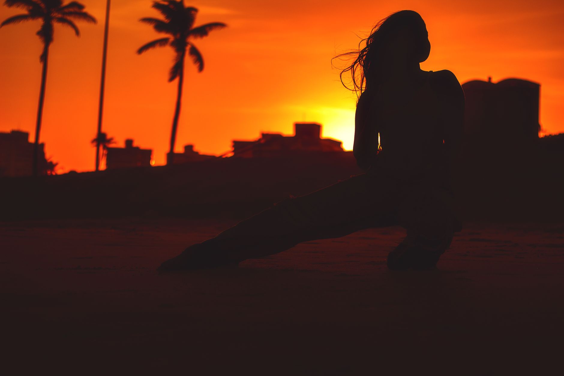 夕暮れの空を背に、片脚を踏み込んで立つ人のシルエット